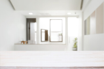 Empty wooden desk space and blurry background of home window for product display montage.