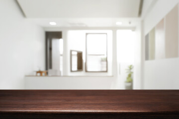 Empty wooden desk space and blurry background of home window for product display montage.