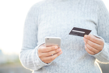 A woman using a credit card to pay for goods online with a mobile phone