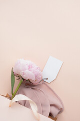 Shopping, sale and fashion concept. Paper bag with womens clothes and peony flower. Top view, flat lay, copy space, vertical