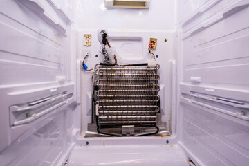 Refrigerator repair. Freezer compartment back panel removed. Evaporator coils with a frozen...