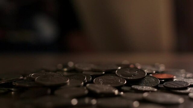 CLOSE-UP of a Pile of coins as quarters keep being thrown at it