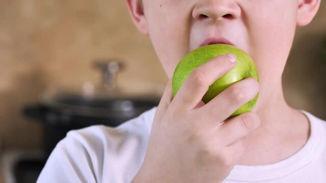 Child boy eating apple fruit at breakfast in kitchen