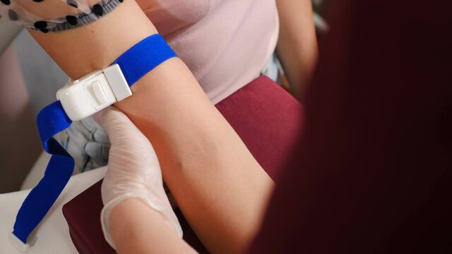 Laboratory in clinic. Female lab assistant applying tourniquet on female patient arm before taking venous blood for test. HIV Hepatitis Test. Healthcare concept. 4 k footage