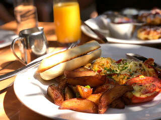 Chorizo, egg, potatoes, tomato breakfast plate on the table with nature shadow from the sunlight. restaurant patio. orange juice and coffee.