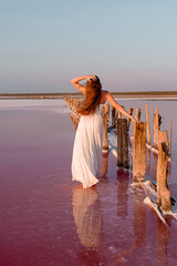 Girl in white dress on a pink lake at sunset