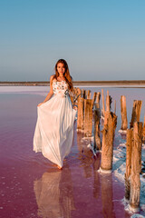 Girl in white dress on a pink lake at sunset