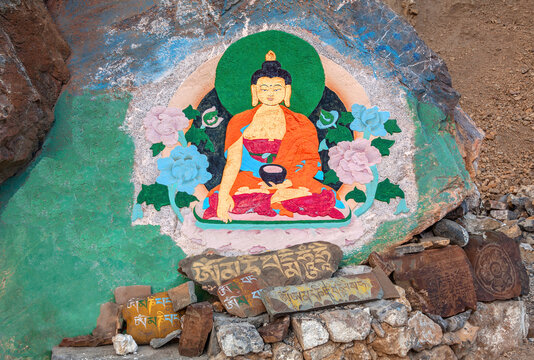 Rock painting of Buddha in a lotus position at the entrance to the ancient Buddhist Key Gompa monastery; prayer Buddhist mantras engraved on the stones including sacred mantra "Om Mani Padme Hum"