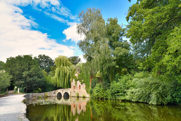 Fototapeta na wymiar Historic ruin called 'Kirchenruine zum heiligen Grab' in front of pond in public park called 'Schöntal' in center of German city Aschaffenburg