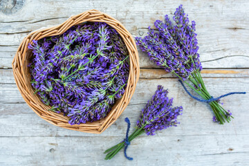 Lavender flowers in a heart-shaped basket on a wooden background.