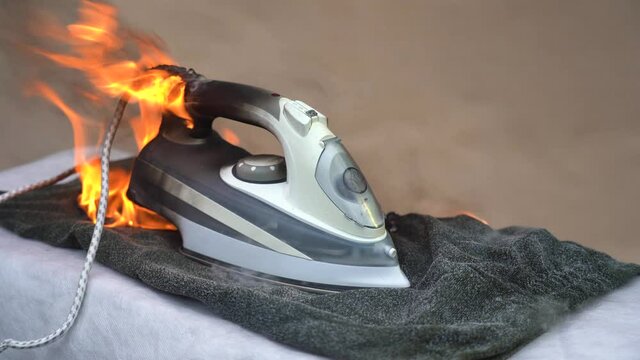 Household appliances on fire. Fire on the iron for ironing clothes. Careless handling of electrical household appliances can cause a fire. The house started a household fire. Bright flames and black
