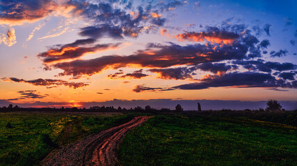 Naklejka na ściany i meble Bright sunlight shining through the clouds against the backdrop of a breathtaking evening sky at sunset. panorama, natural composition