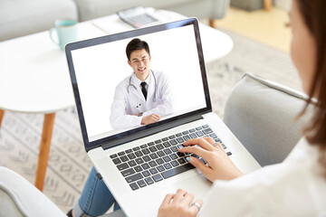 young asian woman talking to doctor via video call using laptop computer