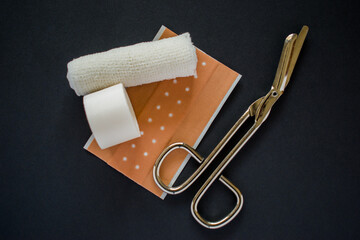 White bandage and medical scissors on black background