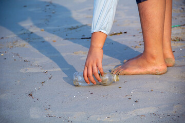 Woman walking garbage on plastic bottles on the beach