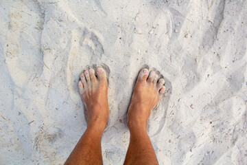 Men feet are standing on the sandy beach