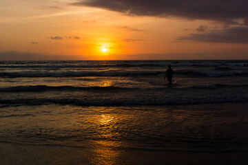 Fototapeta na wymiar Silhouetted woman in the Indian ocean sunset in Bali, Indonesia 