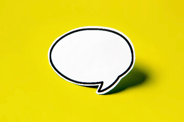 Blank speech bubble on white paper isolated on yellow paper background with drop shadow. COPY SPACE.