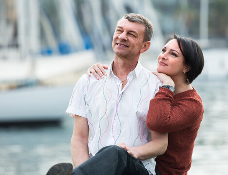 Portrait of loving mature couple hugging against water landscape.