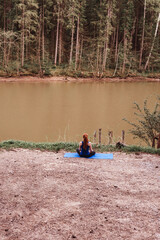 Fototapeta na wymiar Young woman making yoga near river alone. Sport in lockdown. Beautiful evening landscape.