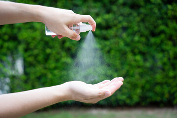 Asian office men clean their hands with alcohol-based hand washing spray as a hygiene measure to...