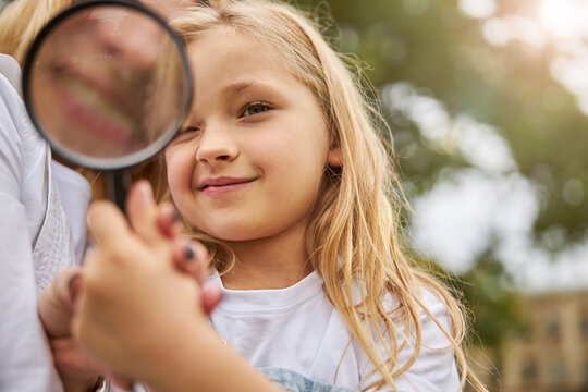 Woman showing for little girl how work with glass magnifying
