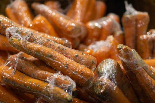Basket with carrot wrapped in plastic in shop