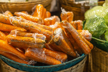 Basket with carrot wrapped in plastic in shop .