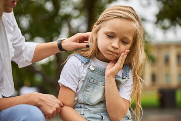 Female child holding hand on the face while feeling pain in the teeth