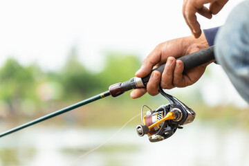 Fishing reel and rod in fisherman hand in a pond