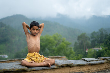 A young indian cute kid doing yoga in the mountains,wearing a dhoti