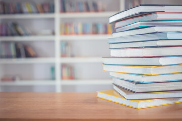Book stack on the table in the library room and blurred space of bookshelf background