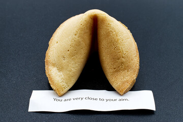 Cracked chinese fortune cookie with the message stating that you are very closed to your aim