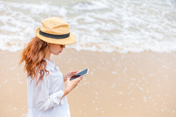 Women using mobile phones on the beach While traveling