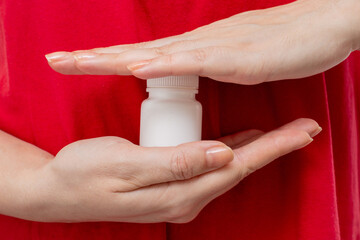 A body in a red t-shirt is holding a white bottle