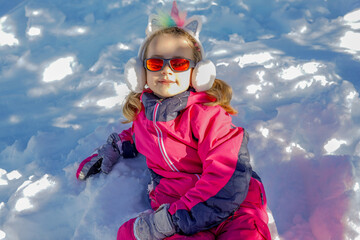 Fototapeta na wymiar Young girl with sunglasses sitting on the snow place