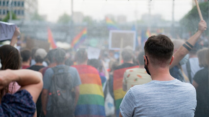 LGBT equality march. Young people wearing rainbow clothes and symbols are fighting for LGBTQ+ rights. Rainbow flags, banners.