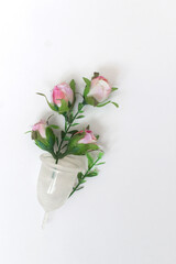 female personal hygiene products isolated on a white background menstrual cup and a pink flowers as a choice eco-friendly zero waste reusable product for a period of time.