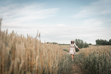 Obraz premium Beautiful young brunette girl in a wheat field walking on the trail