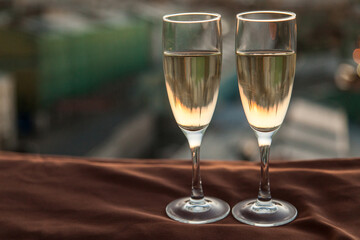 Two glasses of champagne on the background of city roofs at sunset