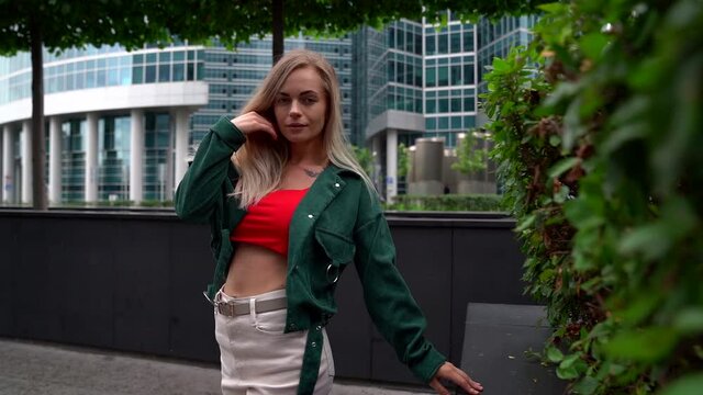 young blonde woman is posing and flirting with camera in city at summertime