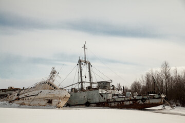 Abandoned white ship frozen in ice near lighthouse