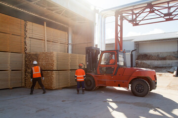 Fototapeta na wymiar workers load boards with an industrial loader at a sawmill