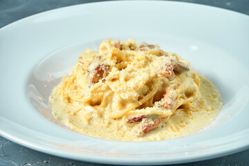 Italian pasta carbonara with white sauce, parmesan and bacon in a white plate. Homemade spaghetti
