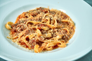 Pasta (tagliatelli) bolognese with red sauce and minced meat in a white plate
