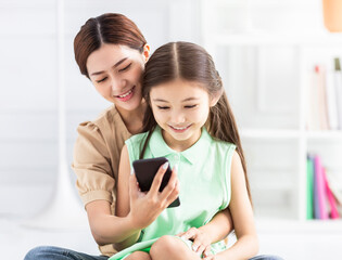 happy mother and daughter watching the smart phone