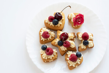 Delicious sweet desserts with cream, decorated with fresh berries, on a white plate and a light background 