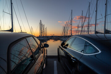Luxury cars and yachts in a port at sunset