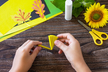 Instructions, step 4. Gift from a paper, sunflower flower on a wooden table. Childrens art project,...