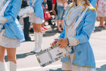 Street performance of festive march of drummers girls in blue costumes on city street. Close-up of...